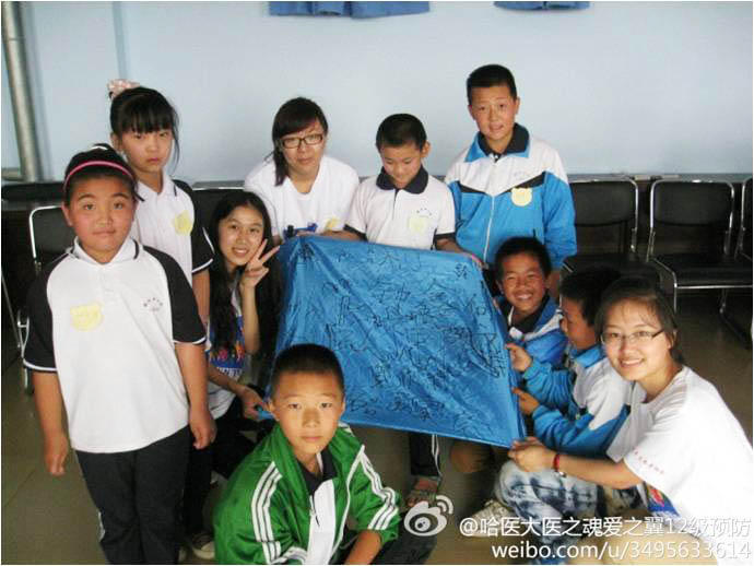 哈爾濱醫(yī)科大學(xué)“醫(yī)之魂·愛之翼”社會實踐團(tuán)隊, 7月8日來到哈爾濱雙城市聯(lián)興學(xué)校進(jìn)行支教活動。團(tuán)隊提出分組陪伴教育的方案,將孩子們分成四個小組。圖為一個小組的孩子們和隊員在隊旗上簽下口號和名字。
