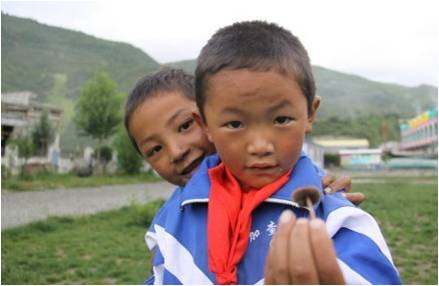 兩個(gè)學(xué)生正在向復(fù)旦大學(xué)的支教隊(duì)員們表達(dá)友好,遞上一只小蘑菇。面對(duì)樸實(shí)的孩子們,支教隊(duì)員們最大的希望是“拉綏因我們多彩,我們因拉綏豐實(shí)”。