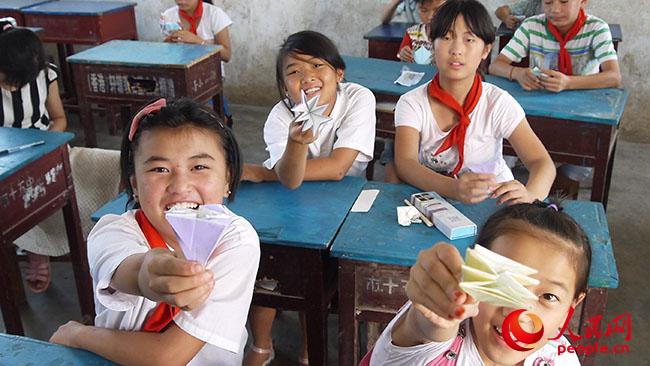 河南科技大學“一帶一路”義務支教與精準扶貧調研實踐團到河南宜陽縣香鹿山鎮磚古窯村開展義務支教和扶貧調研,志愿者給孩子們開設手工課堂,圖為孩子們展示手工作品。(團隊提供)